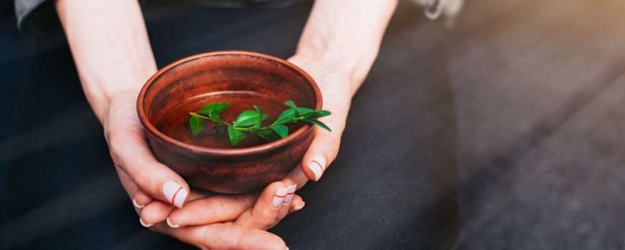 Closeup view of woman holding herbal cup of tea. Concept of alternative medicine. Ceramic cup of hot tea with green leaf